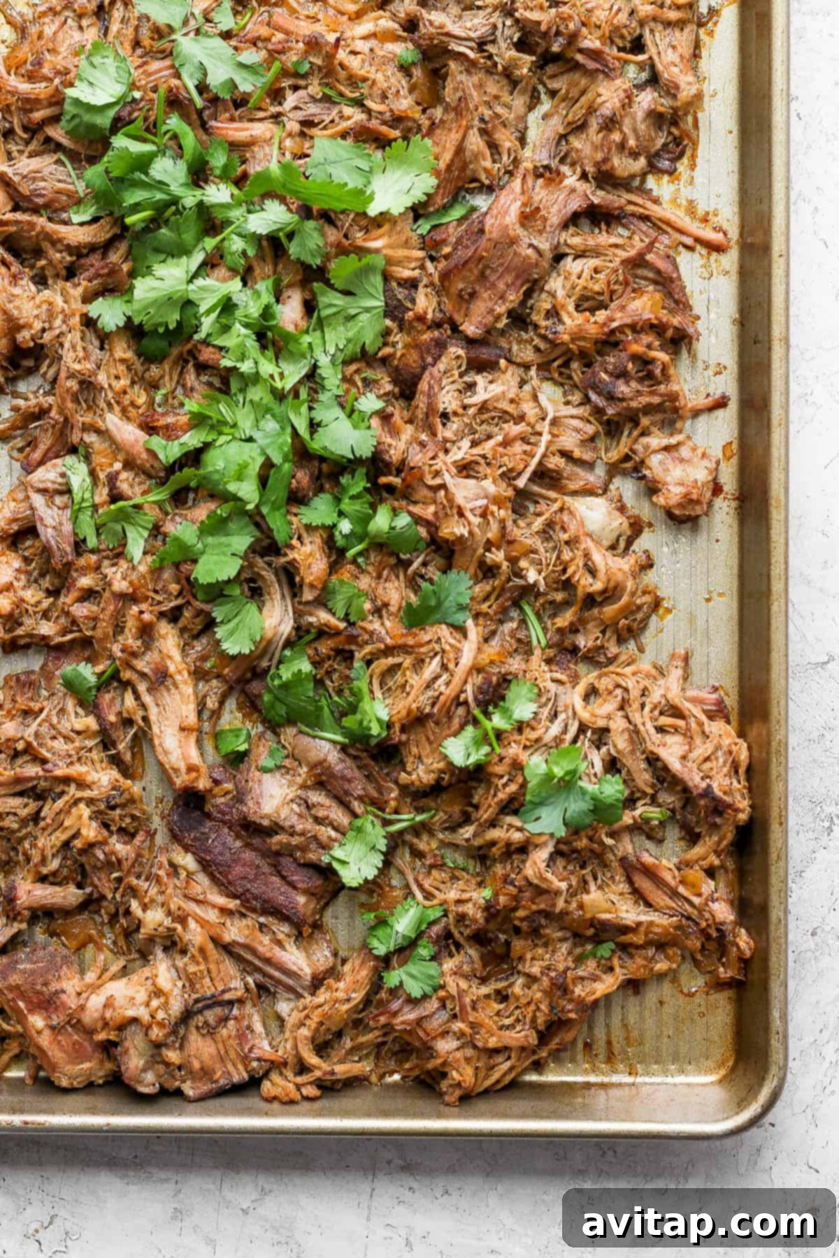 Close-up of crispy slow cooker carnitas on a baking sheet, showcasing their rich, browned texture.