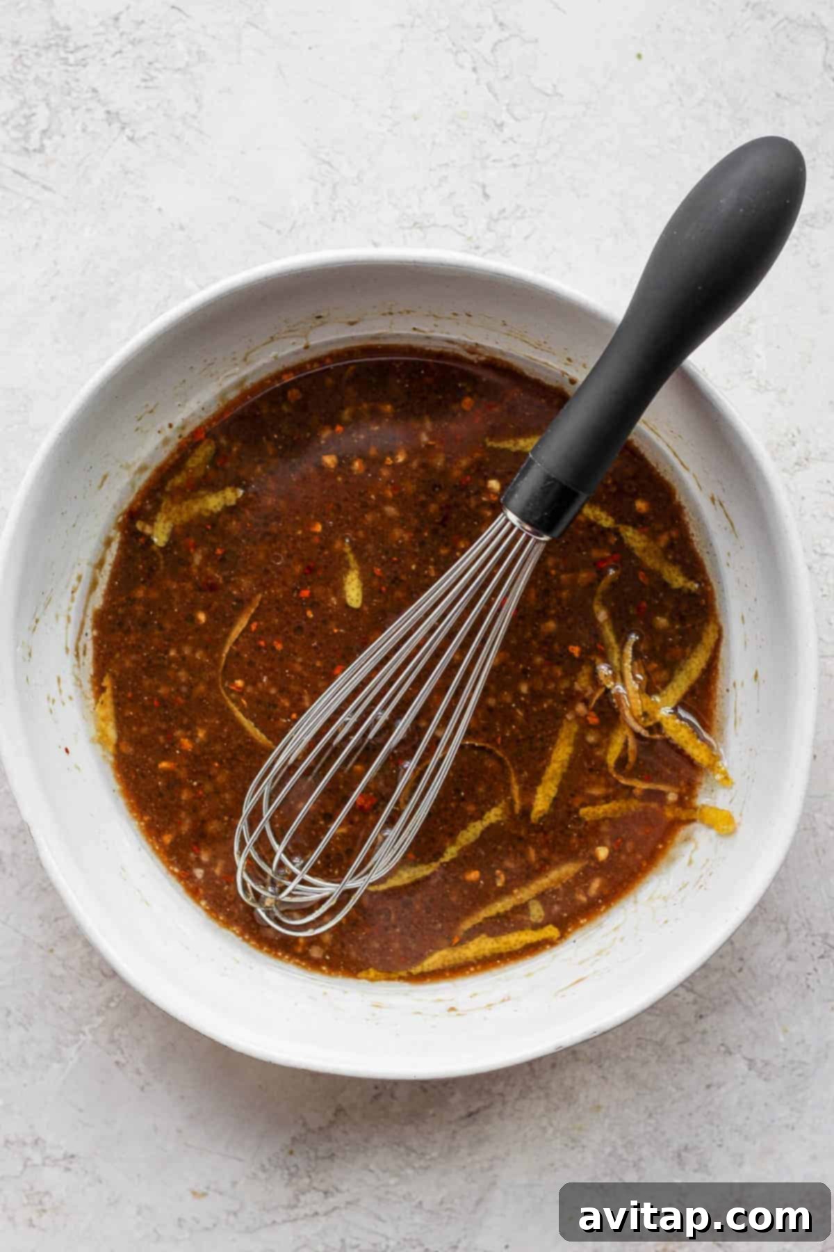 A bowl of freshly mixed chicken marinade with a whisk inside.