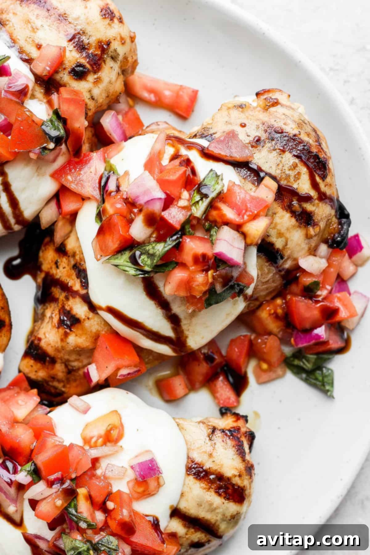 Grilled chicken breast topped with colorful bruschetta and melted mozzarella, garnished with fresh basil.