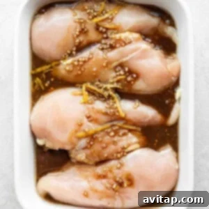 raw chicken in a white casserole dish with sesame seeds.