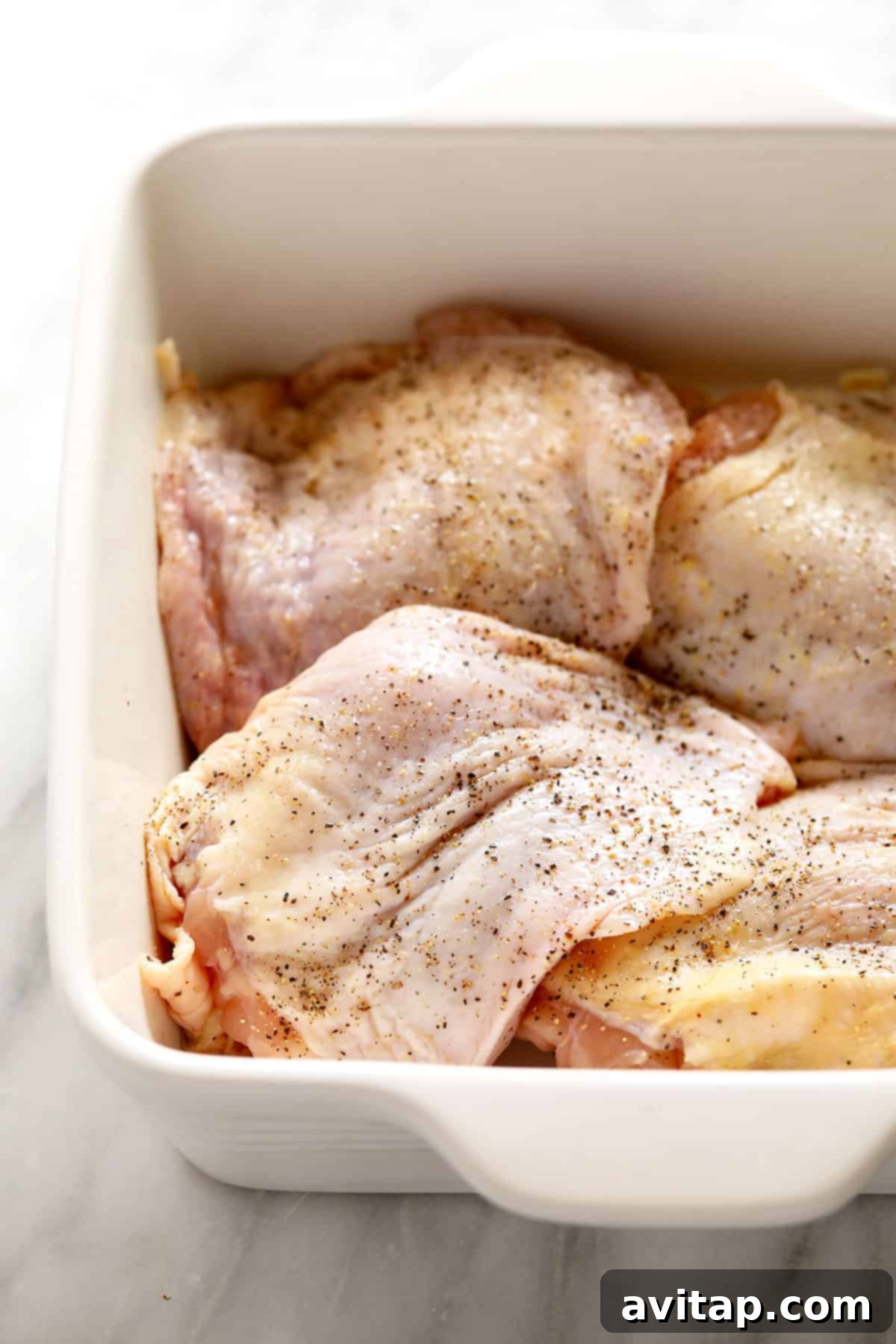 Juicy Smoked Chicken Thighs 3 Raw chicken thighs soaking in a vibrant, homemade marinade within a glass casserole dish, ready for refrigeration.