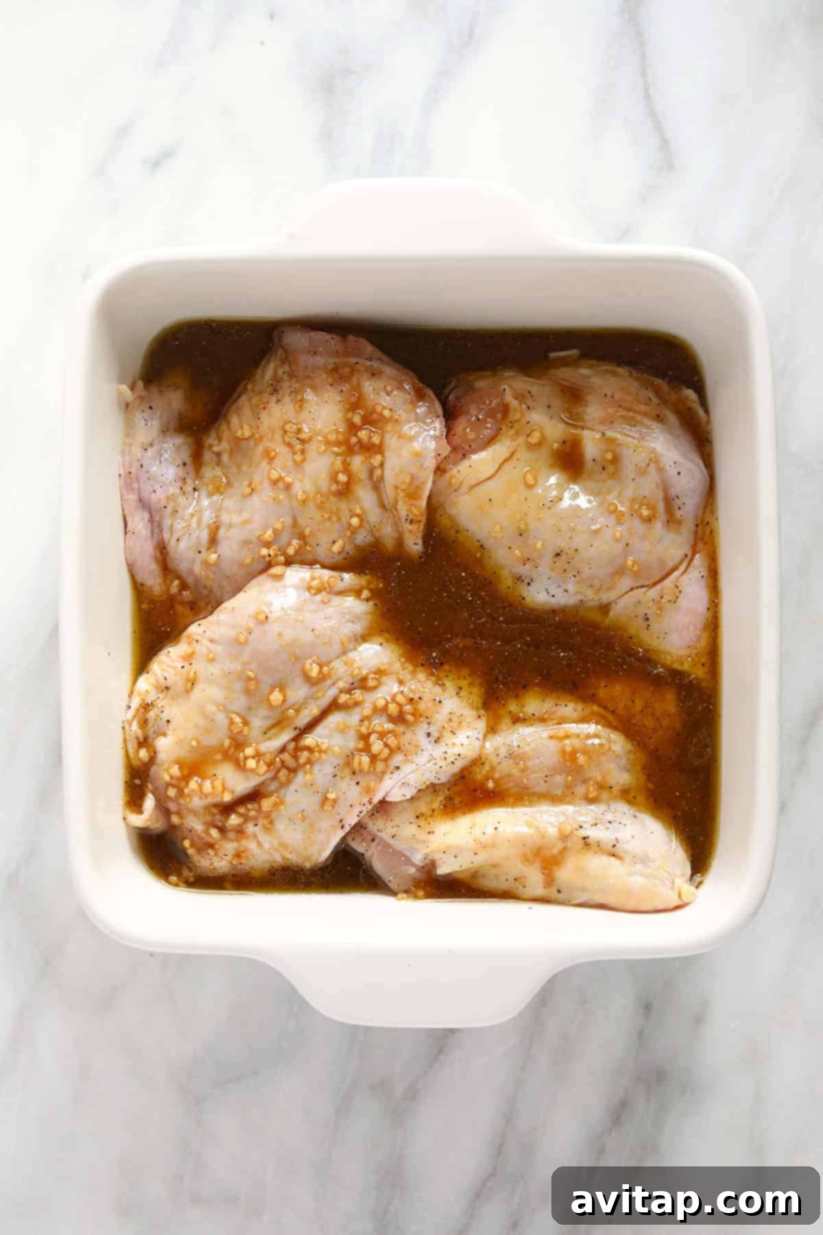 Juicy Smoked Chicken Thighs 5 Raw chicken thighs coated in a rich, dark marinade, arranged in a baking dish, ready for smoking.