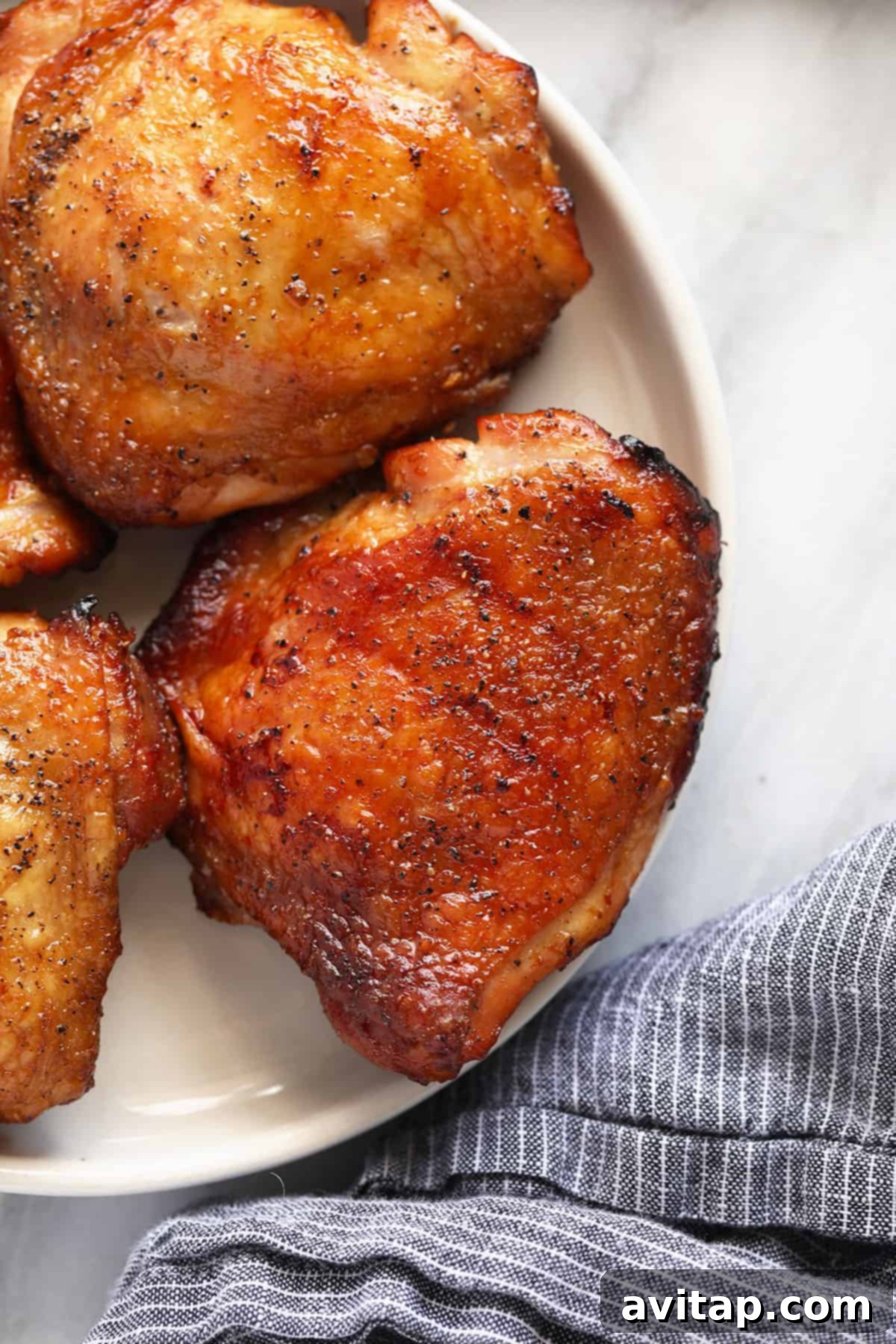 Juicy Smoked Chicken Thighs 8 Three perfectly smoked chicken thighs, beautifully browned with crispy skin, presented on a white plate ready to be enjoyed.