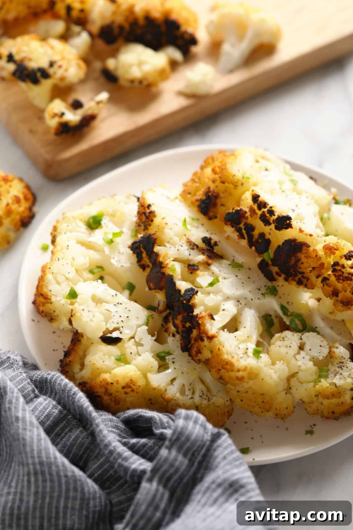A plate of perfectly grilled cauliflower steaks, lightly charred and seasoned, ready to be served.