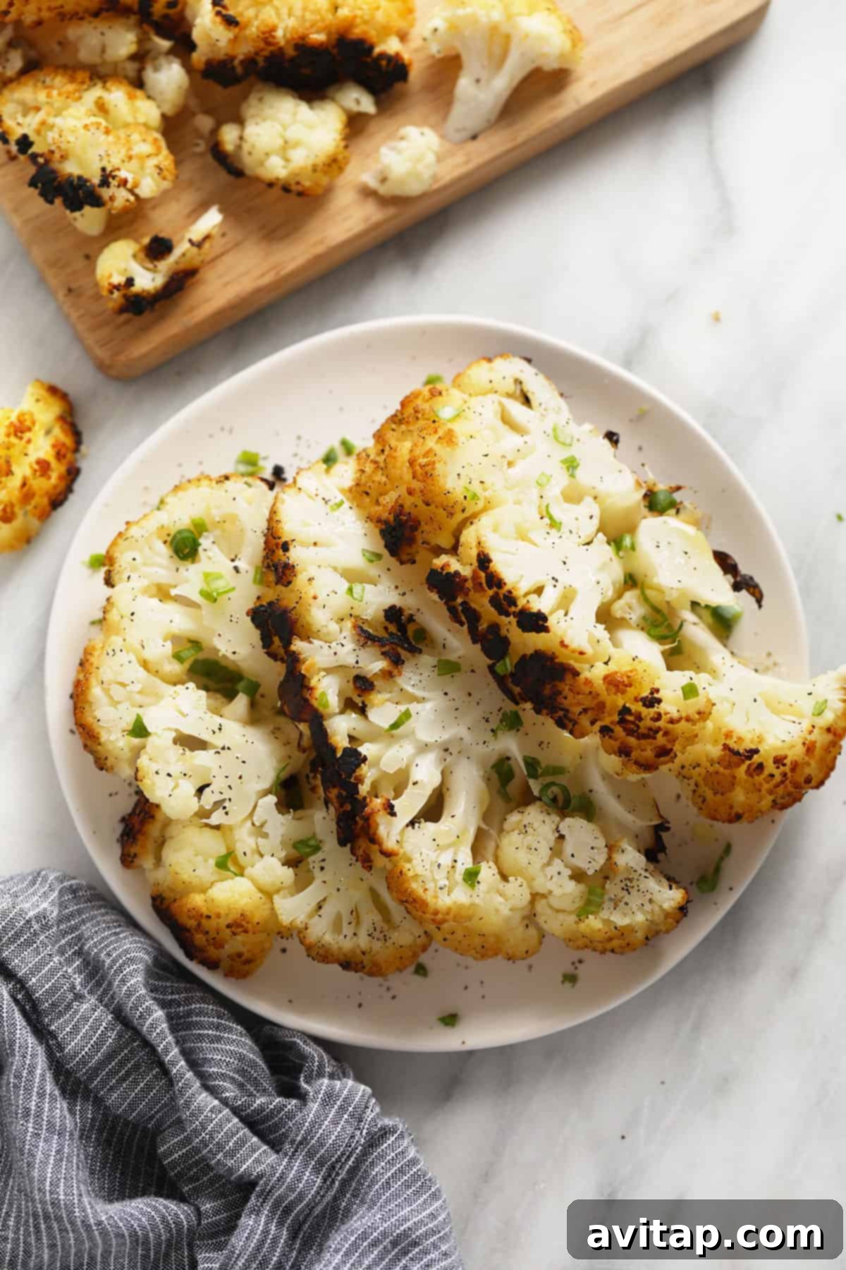 A beautifully arranged plate featuring tender, charred grilled cauliflower steaks, garnished and ready for a meal.