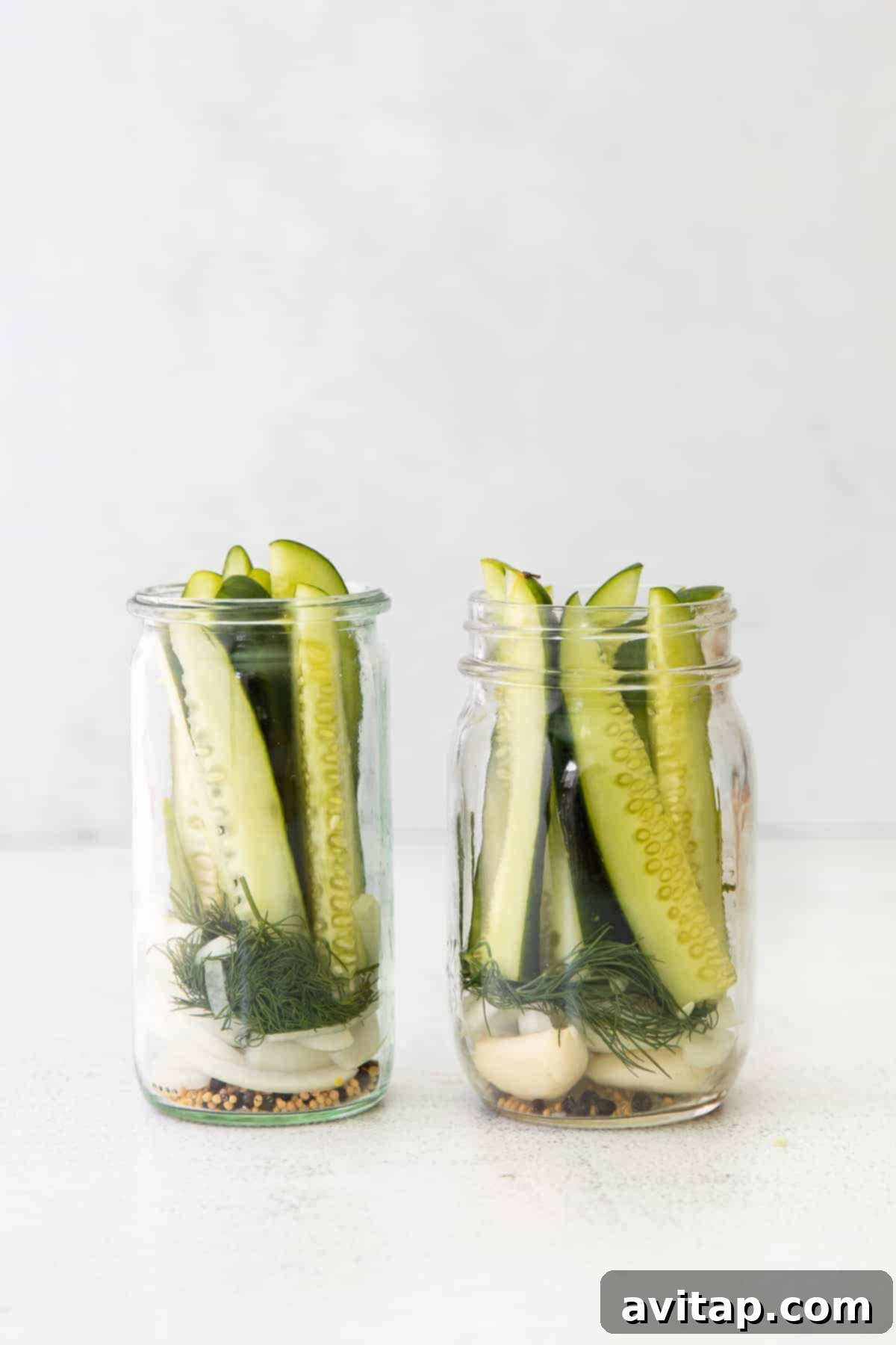 Refrigerator pickle ingredients neatly arranged in two mason jars, ready for the brine.