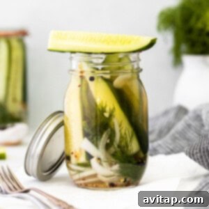 Refrigerator pickles in a jar, showcasing the vibrant green cucumbers and aromatic spices.