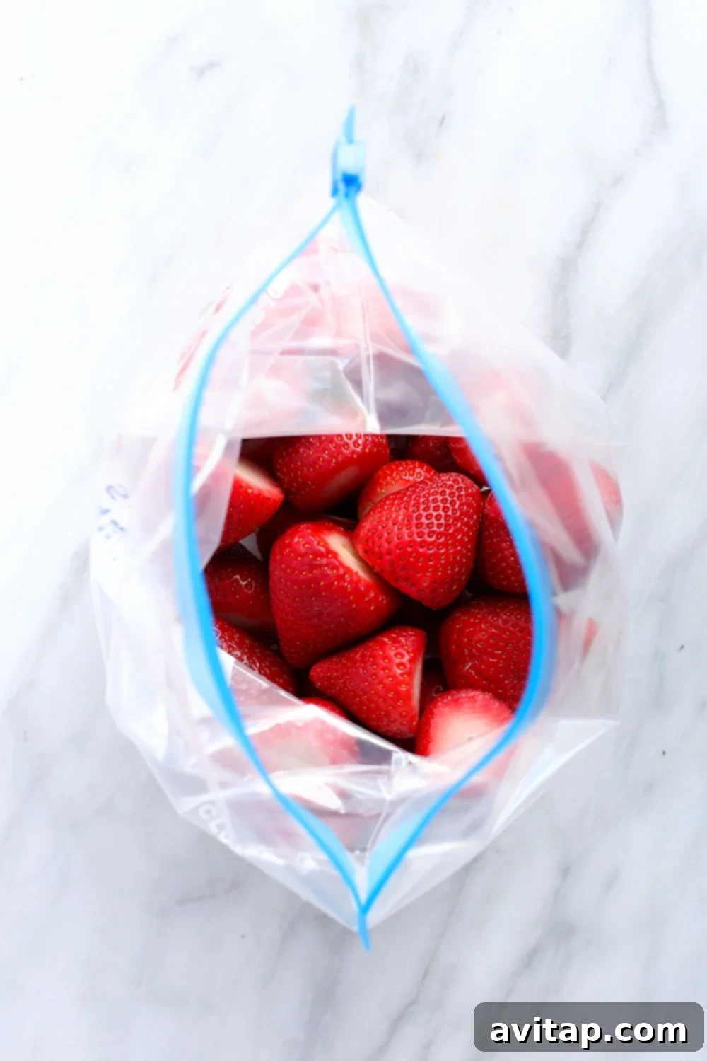 A transparent freezer bag clearly displaying a generous amount of perfectly frozen strawberries, ready for future culinary creations.