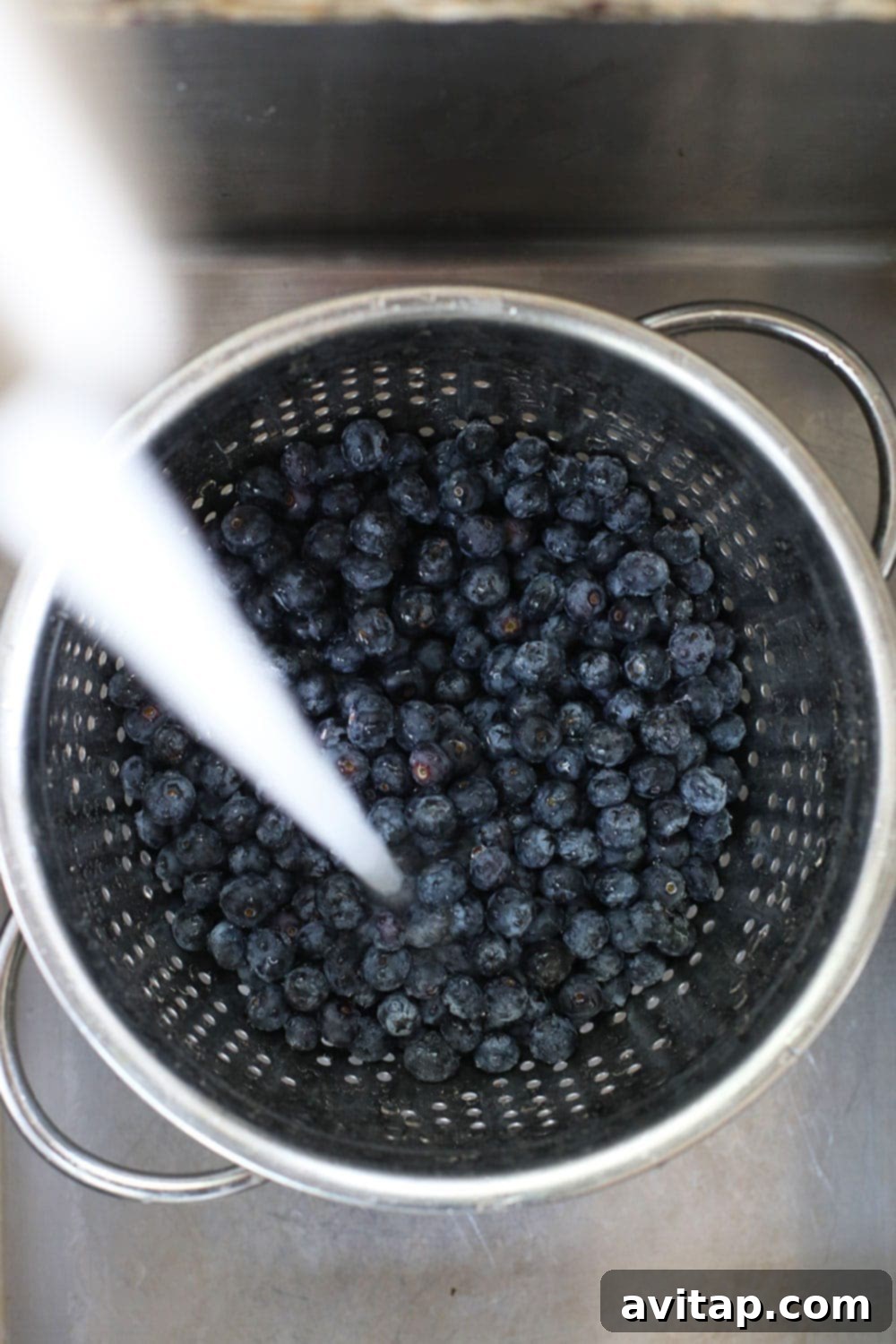 Fresh blueberries being washed in a strainer. blueberries in strainer