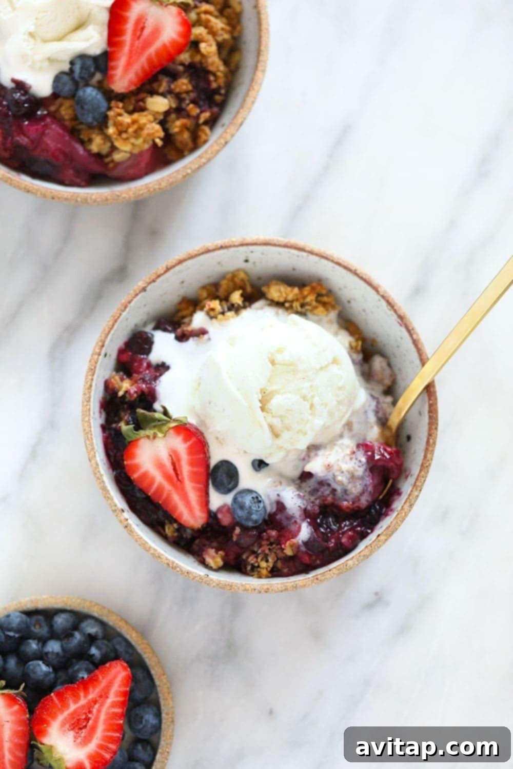 berry crisp in bowl with ice cream on top