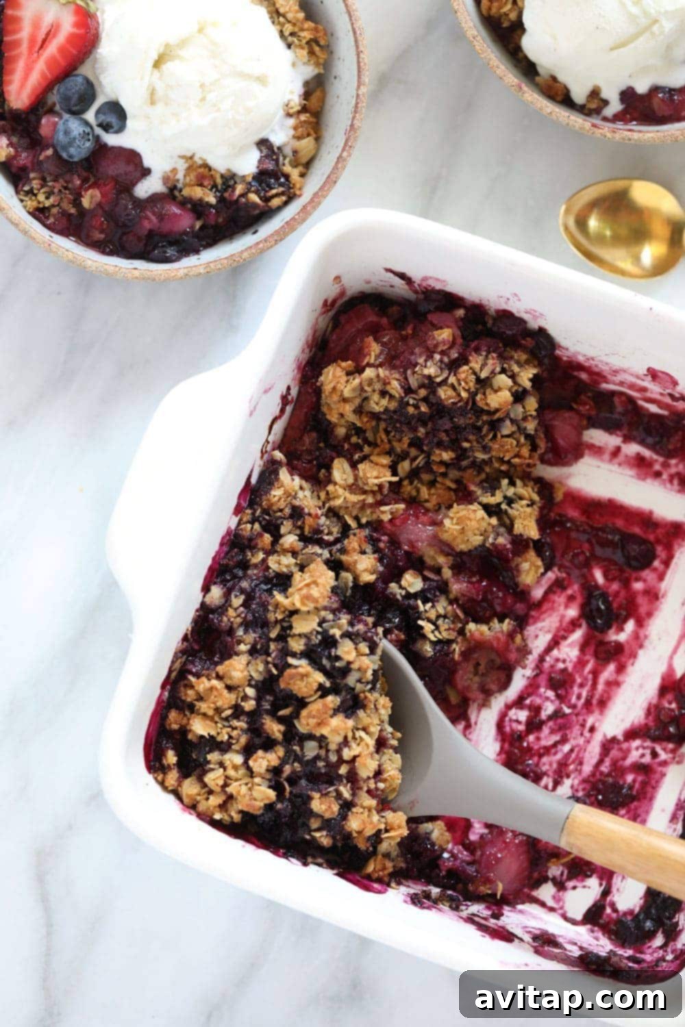 berry crumble in a white dish with serving spoon