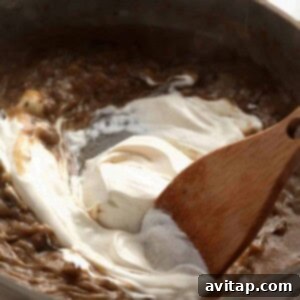 Effortless Creamy Beef Stroganoff 13 Creamy sauce being whisked in a pan for beef stroganoff.