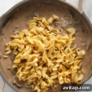 Effortless Creamy Beef Stroganoff 14 A skillet filled with the finished beef stroganoff, noodles mixed in.