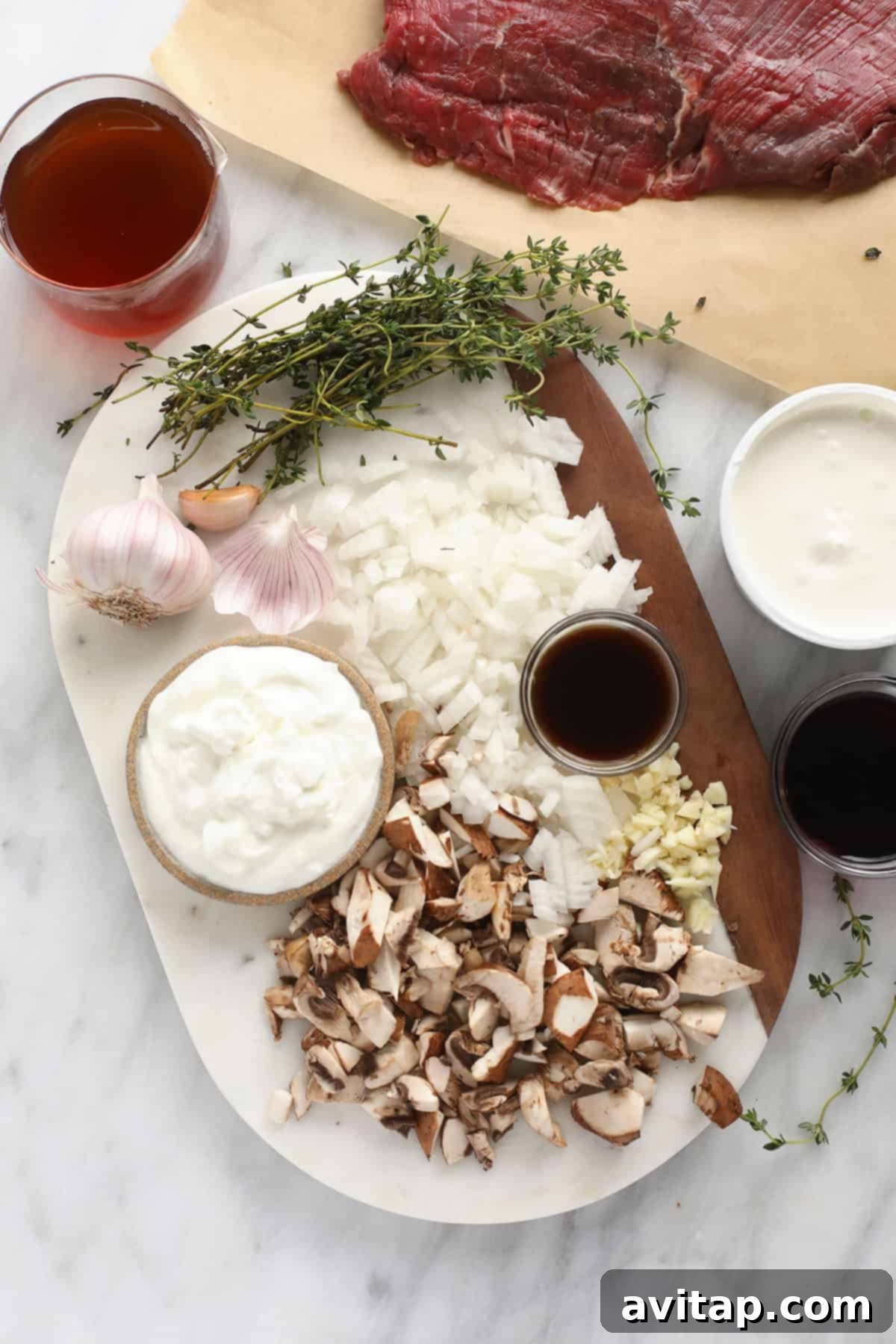Effortless Creamy Beef Stroganoff 3 A selection of fresh ingredients laid out, including sour cream, Greek yogurt, raw beef strips, crimini mushrooms, and Worcestershire sauce, ready for making beef stroganoff.