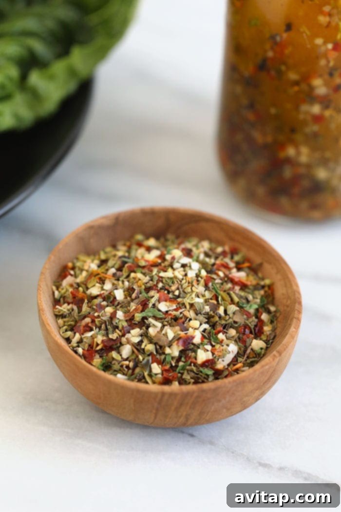 Zesty Homemade Italian Dressing 3 A small wooden bowl filled with a blend of dry Italian seasoning, showcasing various herbs.