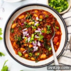 A vibrant bowl of roasted red pepper quinoa chili, perfectly garnished.
