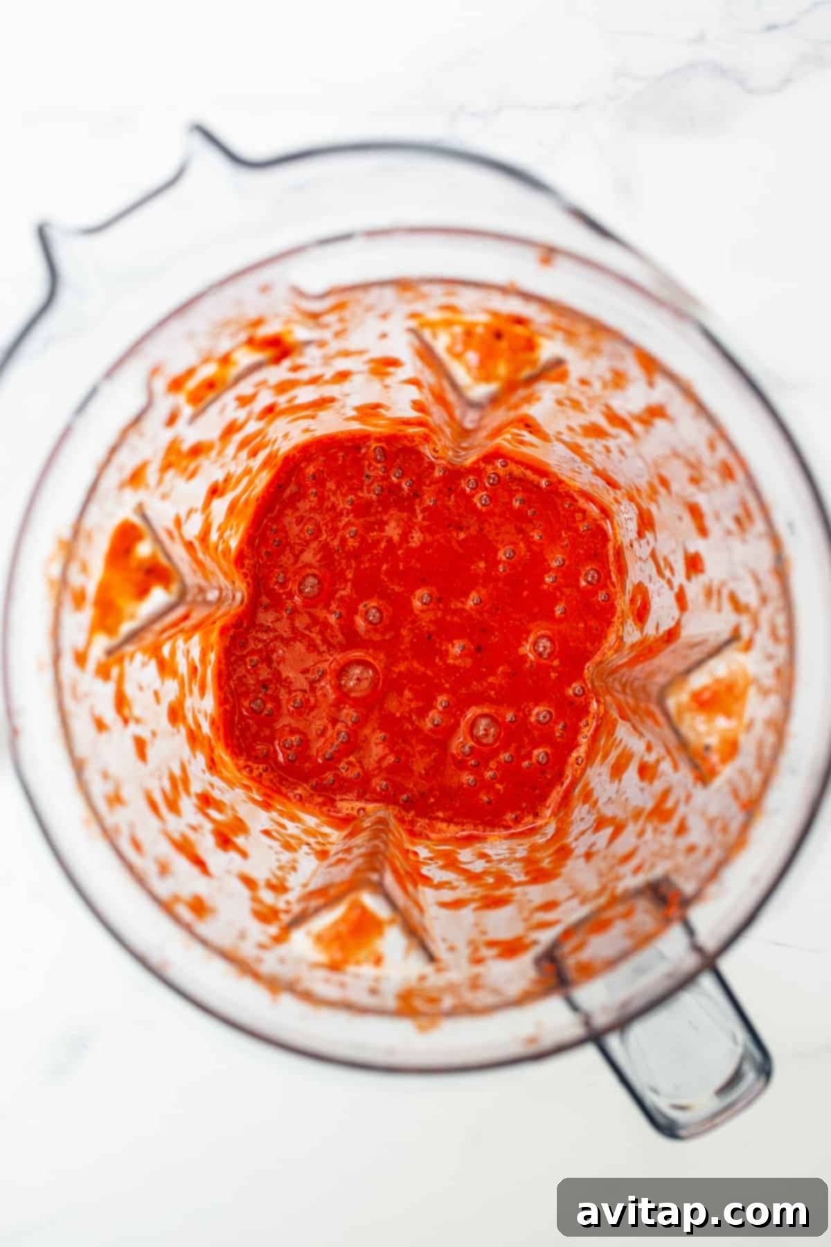 Close-up of vibrant, pureed roasted red peppers in a high-speed blender, ready to be incorporated into the chili.