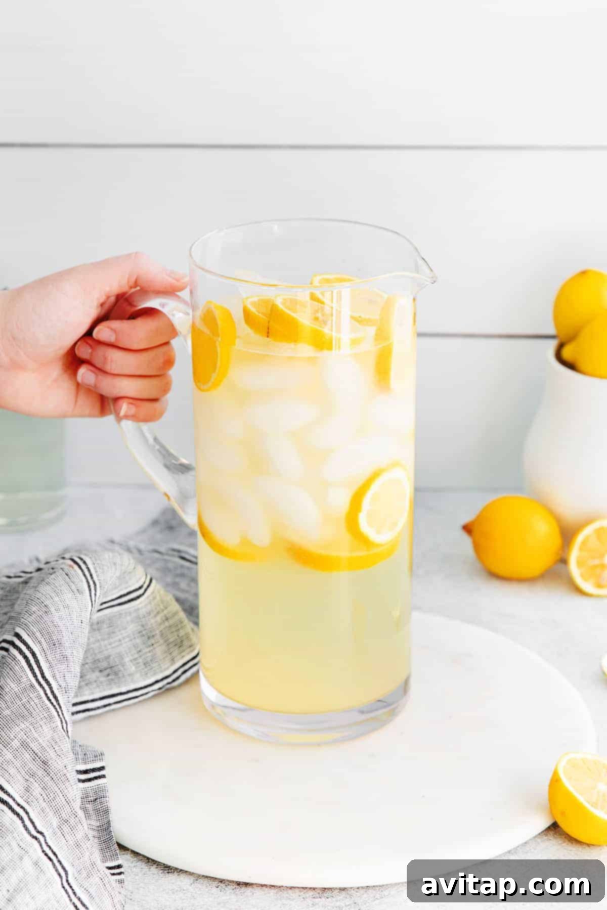 A vibrant pitcher of homemade lemonade, brimming with ice and fresh lemon slices, ready to be served.
