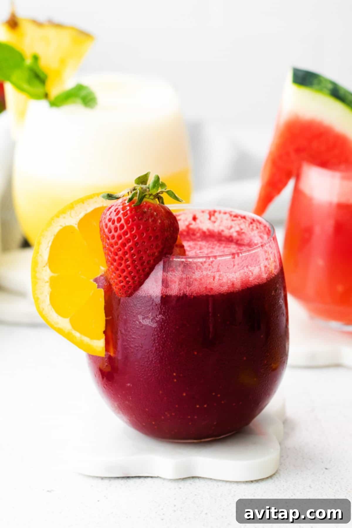 Two glasses of vibrant, colorful wine slushies – one watermelon red and one tropical yellow – garnished with fresh fruit, inviting a refreshing sip.