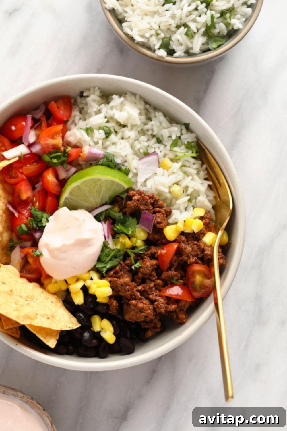 Close-up of a fully assembled taco bowl with ground beef, cilantro lime rice, and fresh toppings.