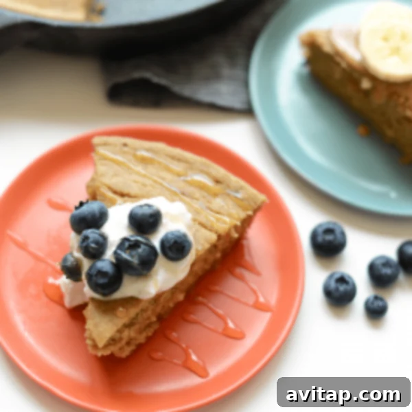 A plate of pancakes with blueberries and whipped cream.