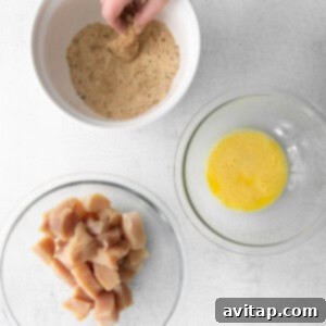 A person's hands mixing spices into a bowl of breadcrumbs, diligently preparing the coating for chicken nuggets.