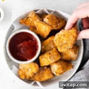 Cooked air fryer chicken nuggets served in a rustic bowl with a side of ketchup, ready to be enjoyed as a snack or meal.