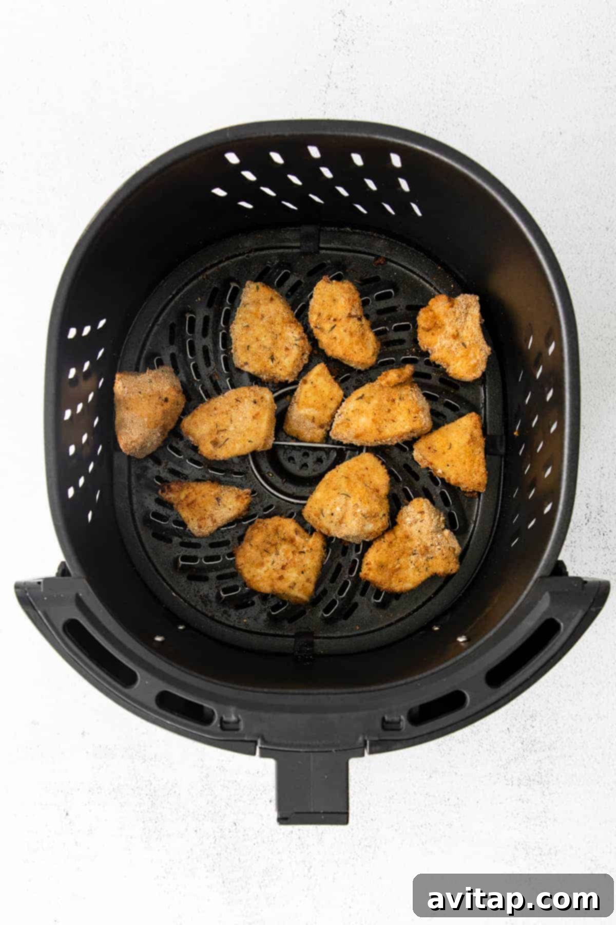 A batch of perfectly cooked, golden-brown air fryer chicken nuggets resting on a clean white plate, ready to be served and enjoyed.