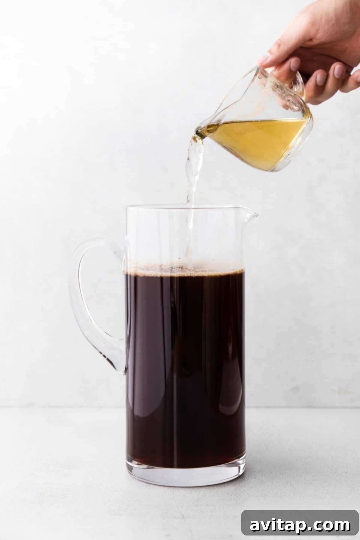 Sweetening Homemade Iced Tea simple syrup being poured into a pitcher of iced tea