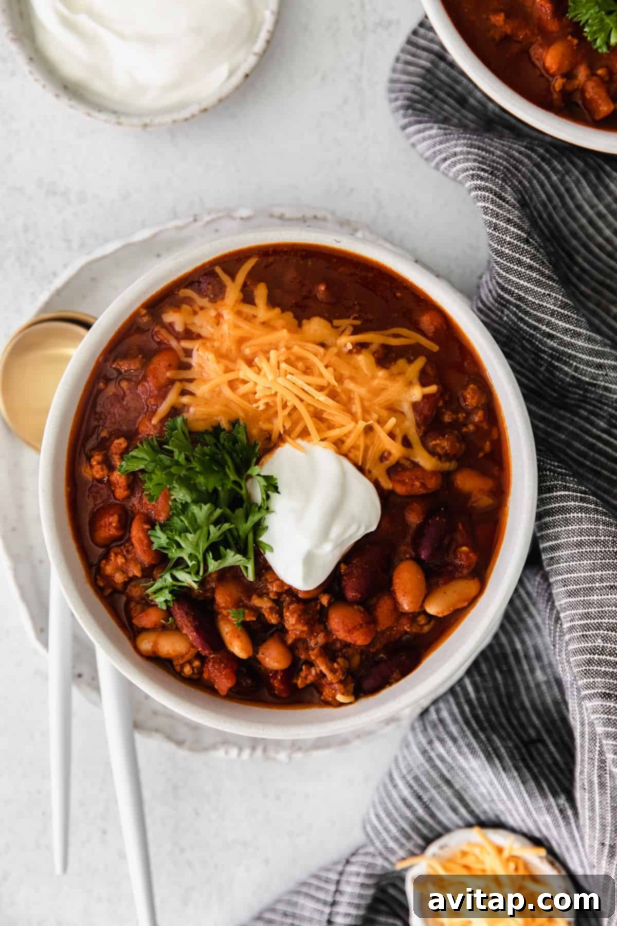 Whip up a batch of this delicious Instant Pot Chili in no time! This Instant Pot Chili recipe is made with ground beef, beans, tomato products, and homemade chili seasoning. Instant Pot chili topped with shredded cheese in a bowl, ready to be served.