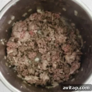 Bowl of instant pot chili with ground beef on a white surface.