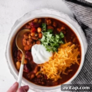 a person holding a bowl of instant pot chili with sour cream.