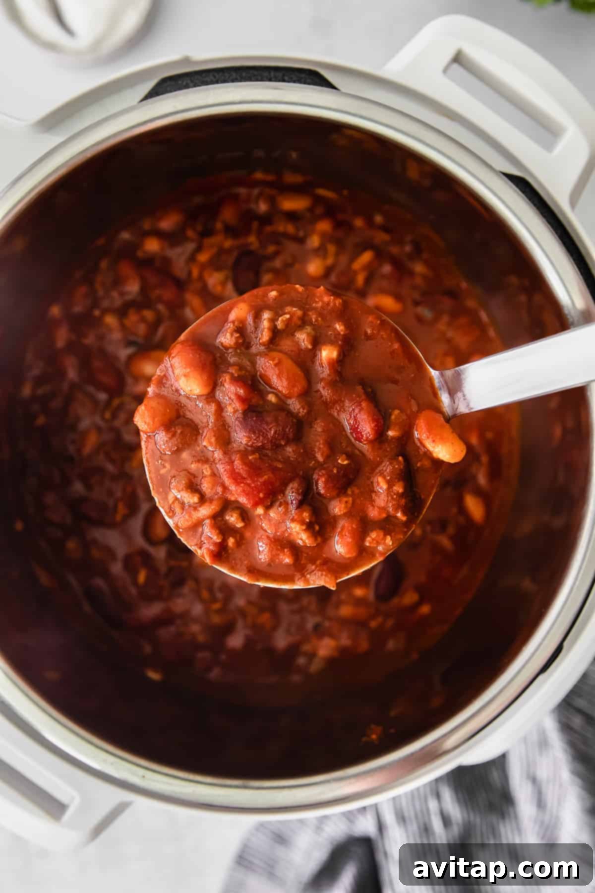 Whip up a batch of this delicious Instant Pot Chili in no time! This Instant Pot Chili recipe is made with ground beef, beans, tomato products, and homemade chili seasoning. A ladle scooping rich, hearty Instant Pot chili from the pot.