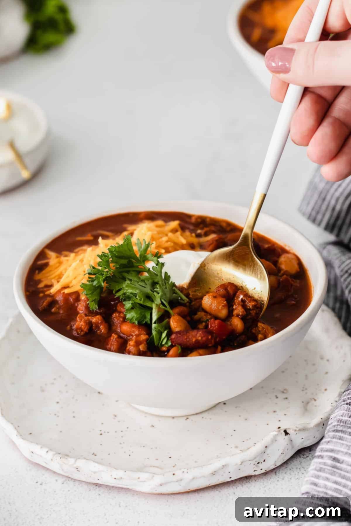 Whip up a batch of this delicious Instant Pot Chili in no time! This Instant Pot Chili recipe is made with ground beef, beans, tomato products, and homemade chili seasoning. A bowl of Instant Pot chili with a spoon, inviting a taste.
