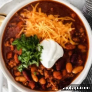 Instant pot chili with sour cream and cheese served in a white bowl.