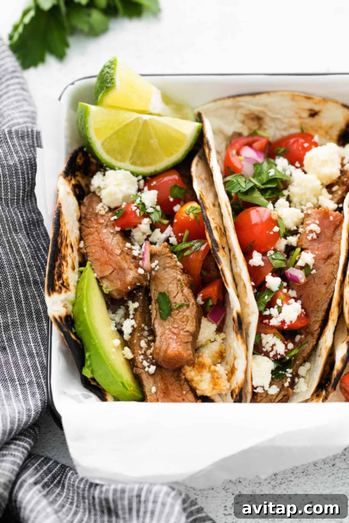 close up photo of steak tacos garnished with fresh lime slices