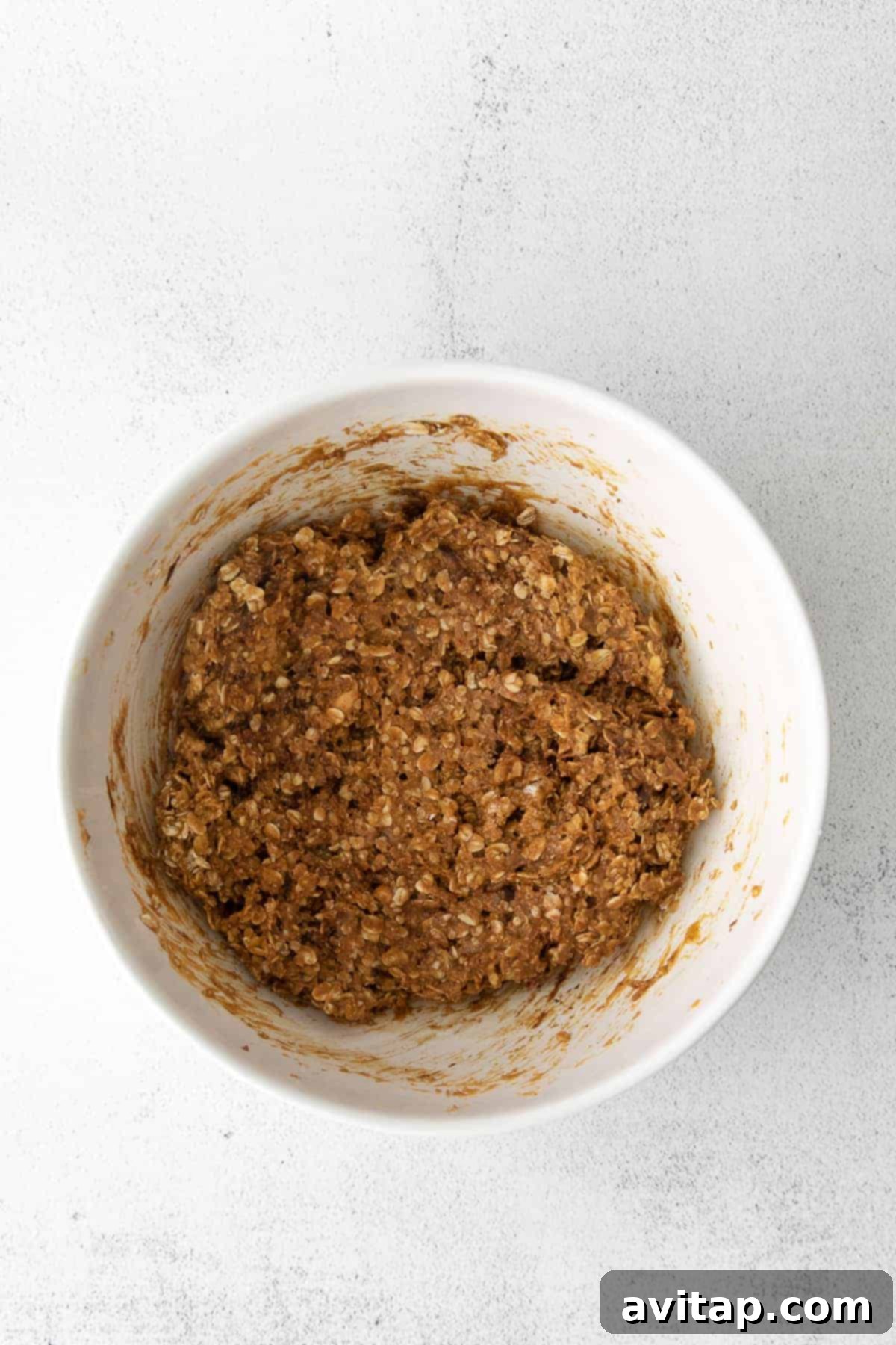 Granola bar mixture in a mixing bowl before pressing into a pan
