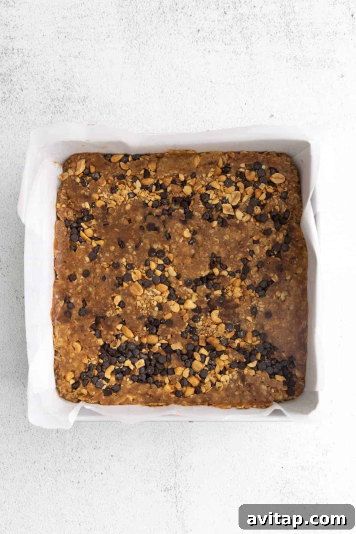 Freshly pressed no-bake granola bars setting in a dish, ready for chilling