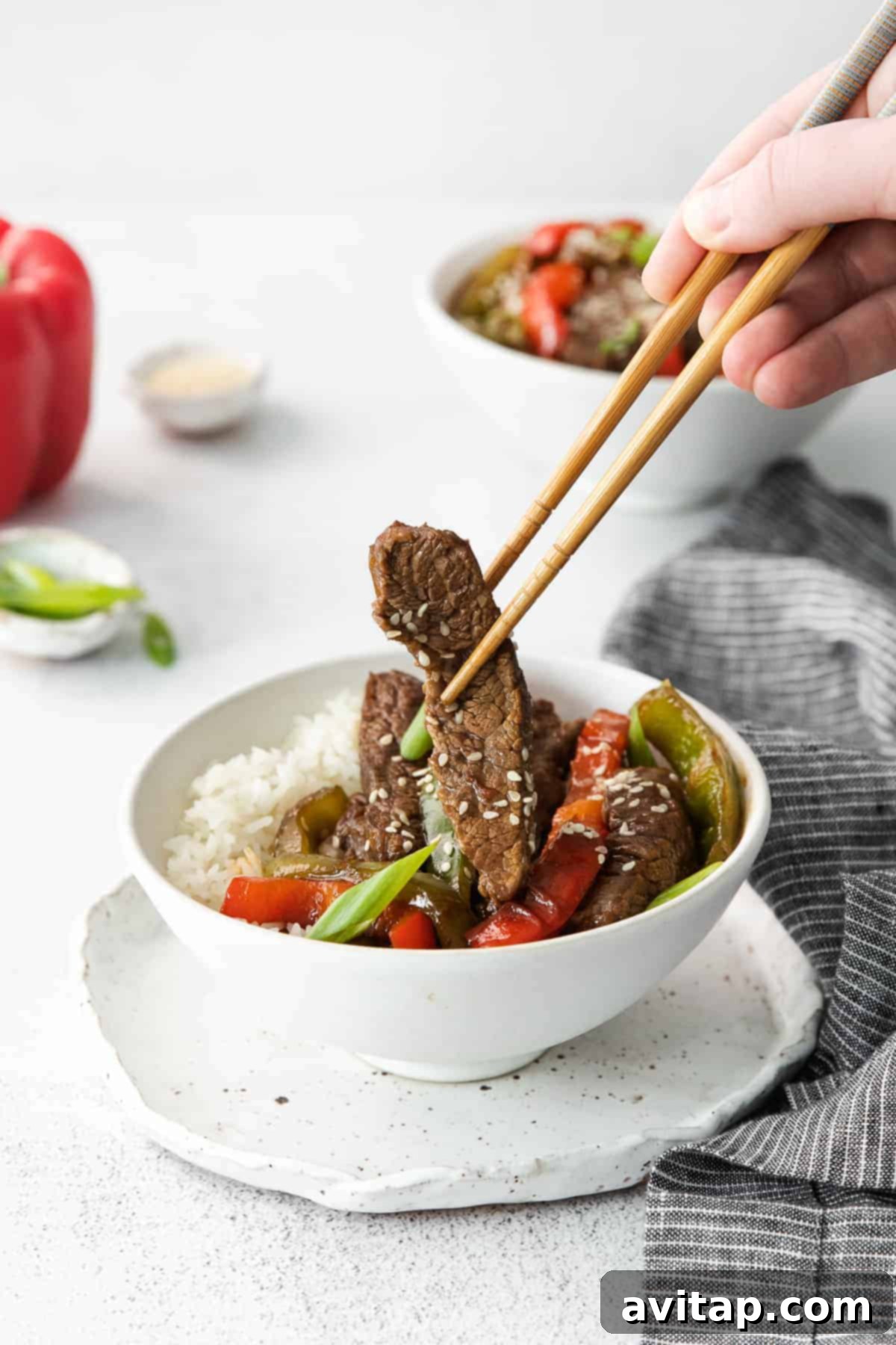 Eating pepper steak with chop sticks.