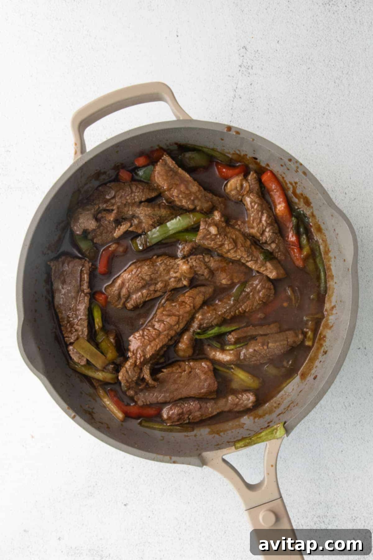 Pepper steak cooking in a fry pan.