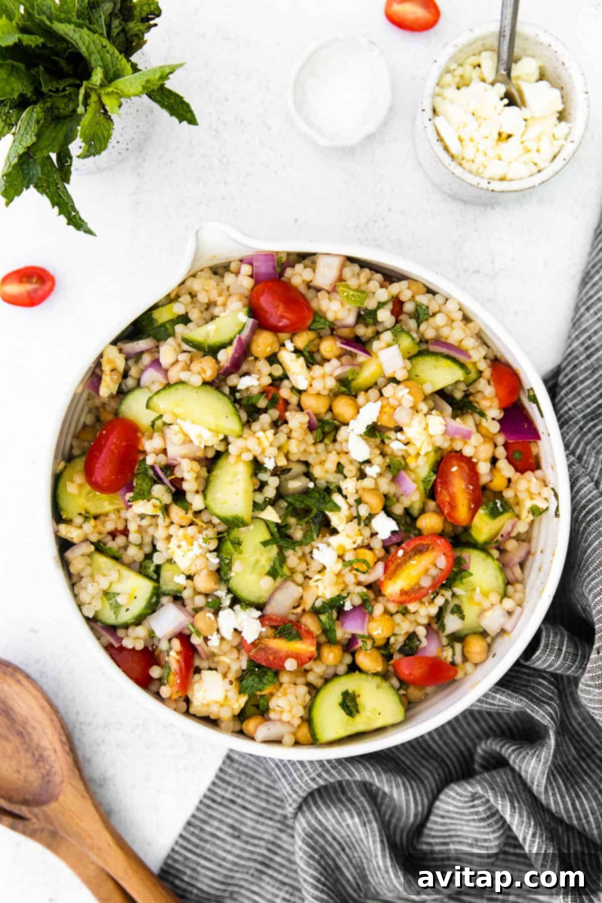 Vibrant Mediterranean couscous salad in a rustic bowl, garnished with crumbled feta and fresh herbs