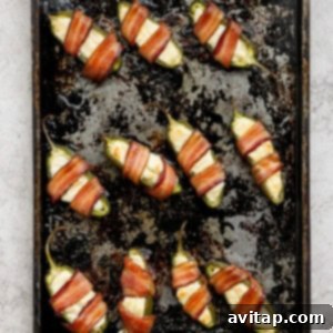 Freshly baked bacon-wrapped jalapenos on a baking sheet, golden and crispy.
