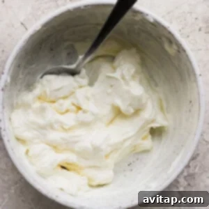 Cream cheese, Greek yogurt, and garlic powder being mixed in a bowl.