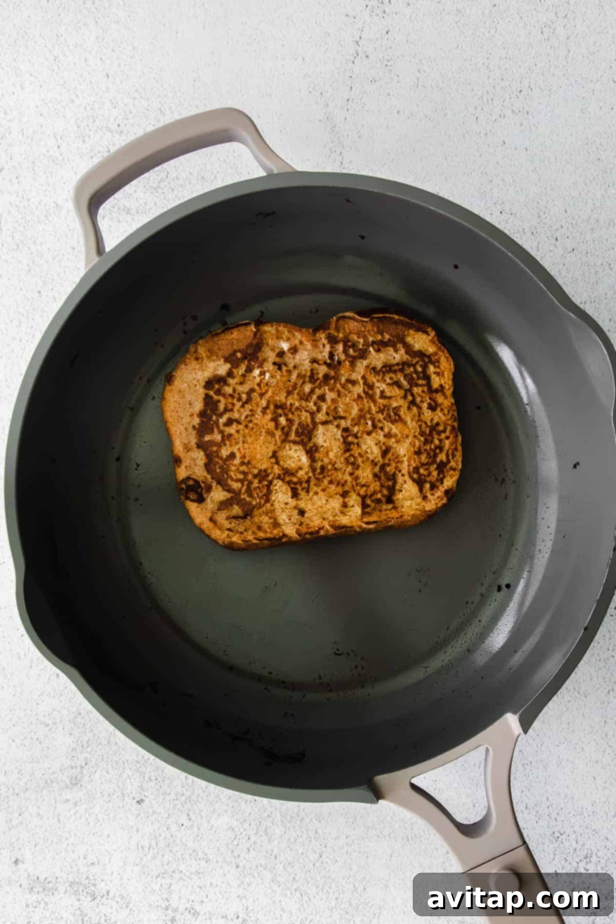 Pumpkin french toast cooking in a non-stick skillet pan, turning golden brown.
