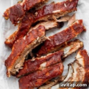 A close up of sliced, juicy oven baked ribs on a cutting board.