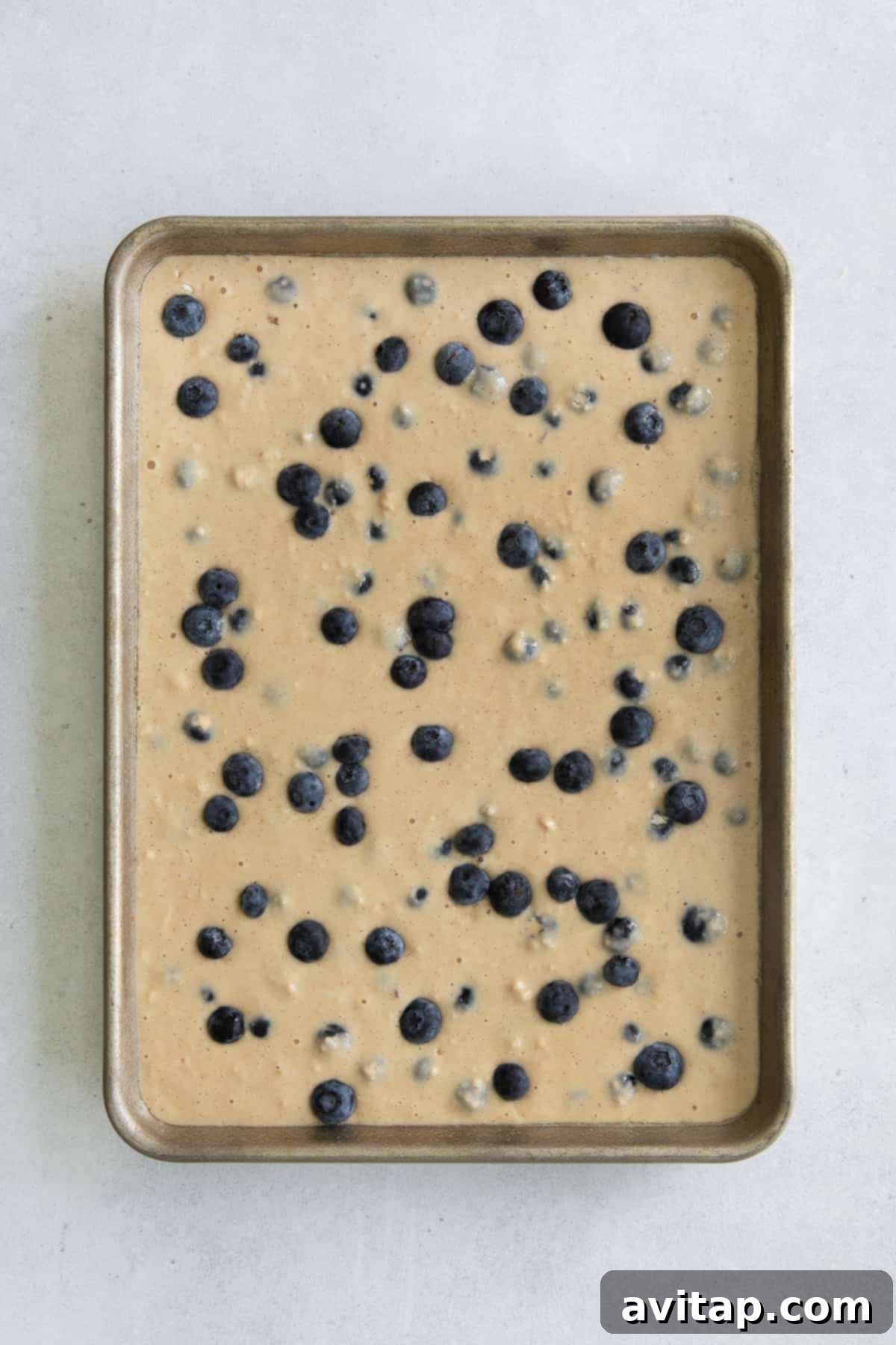 Smooth pancake batter spread evenly on a sheet pan, ready for the oven.