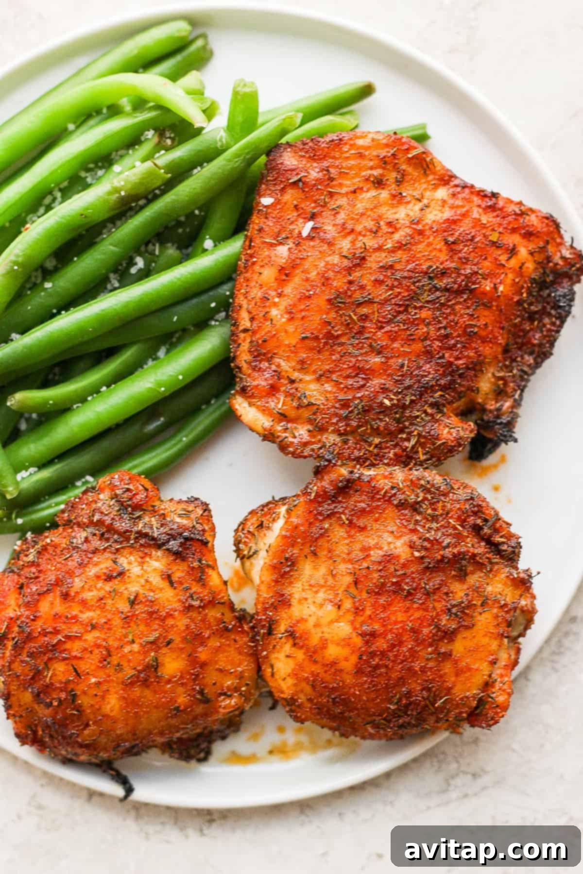 A wholesome meal featuring perfectly crispy air fryer chicken thighs paired with vibrant green beans, a perfect weeknight dinner. A plate of crispy air fryer chicken thighs served with fresh green beans, creating a complete and healthy meal.