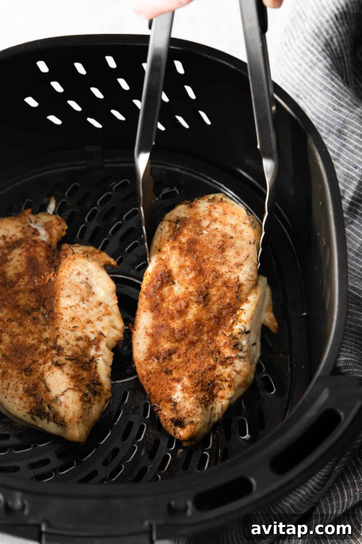 Perfectly cooked, golden-brown chicken breast cooling in the air fryer basket.