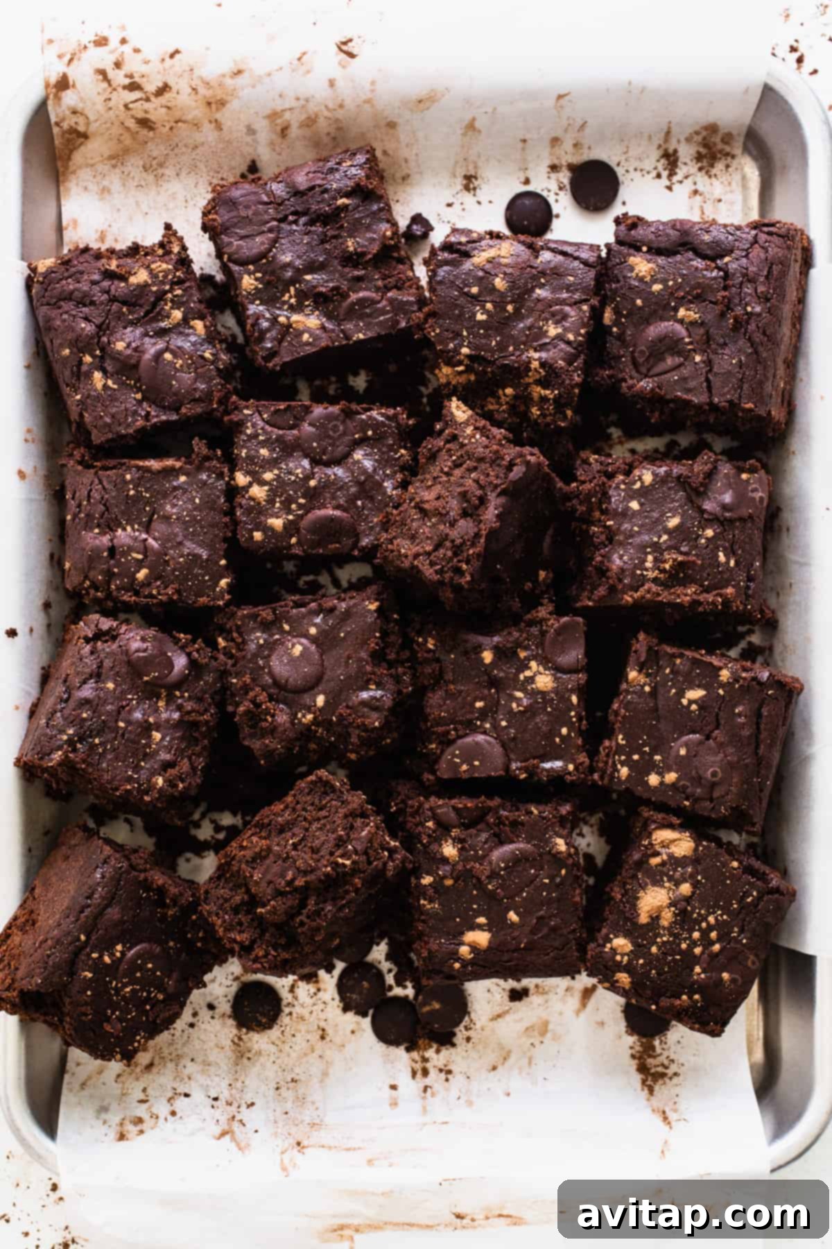 A pan filled with fudgy pumpkin brownies, generously topped with chocolate chips, cooling after baking.
