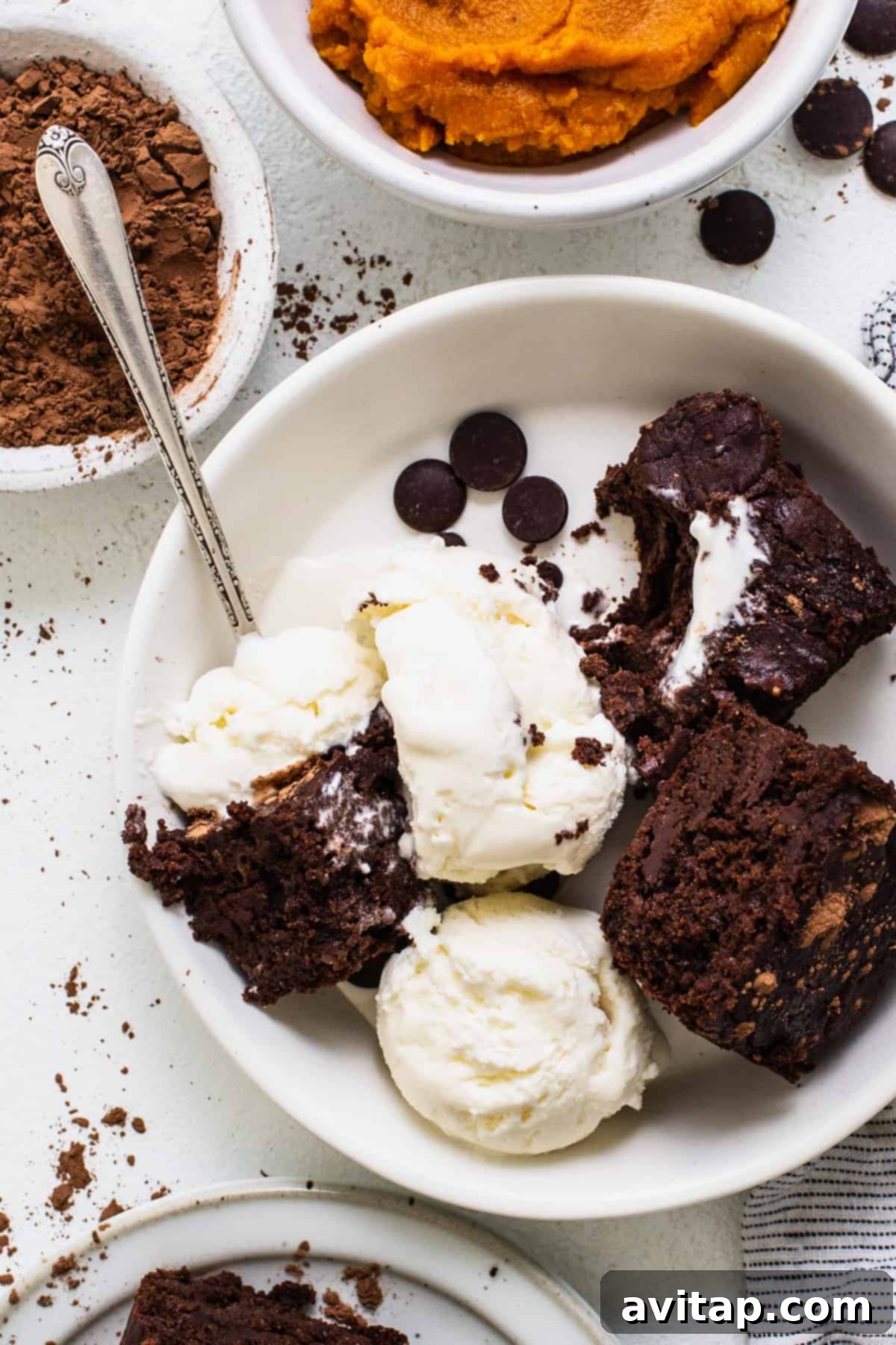 A delectable white bowl brimming with warm brownies and a scoop of melting vanilla ice cream, creating a perfect dessert pairing.
